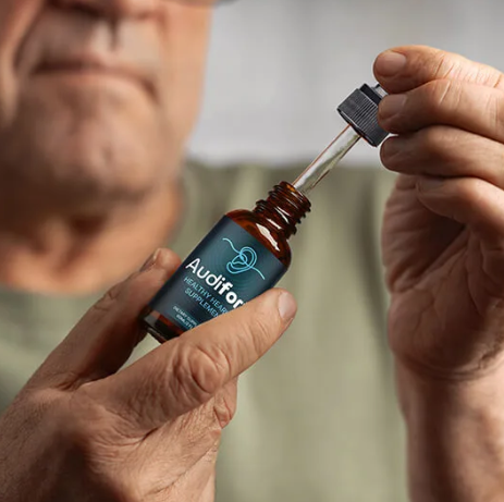 Person holding Audifort bottle and dropper - healthy hearing supplement